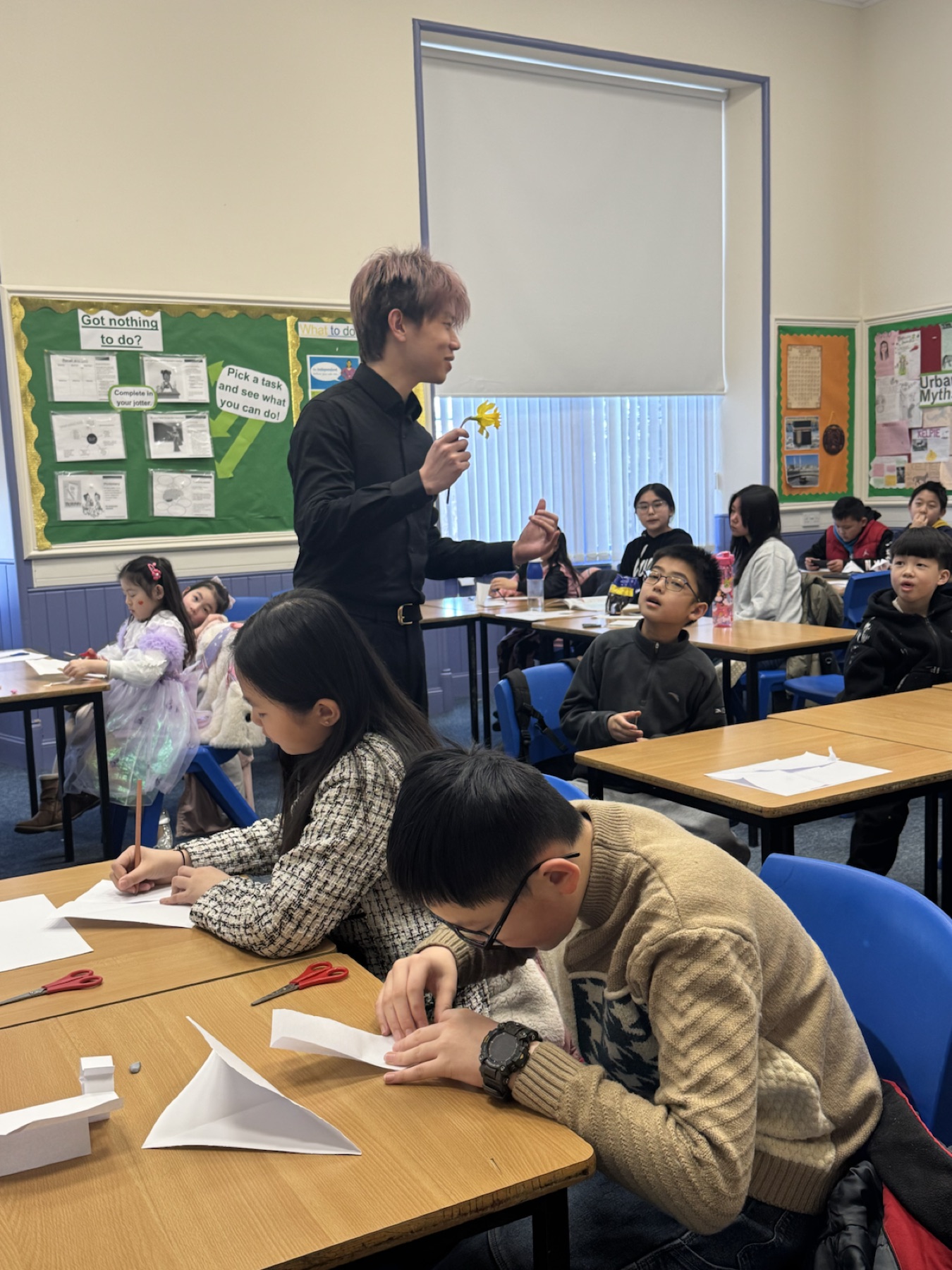 Vince holding a daffodil while teaching pupils in class