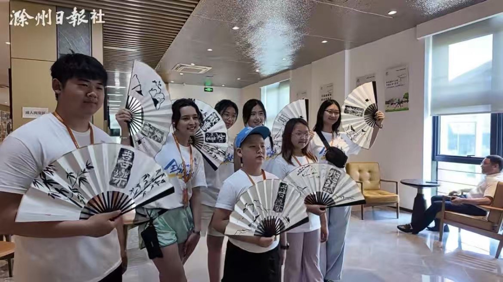 Students and teachers holding traditional painted folding fans at a cultural activity